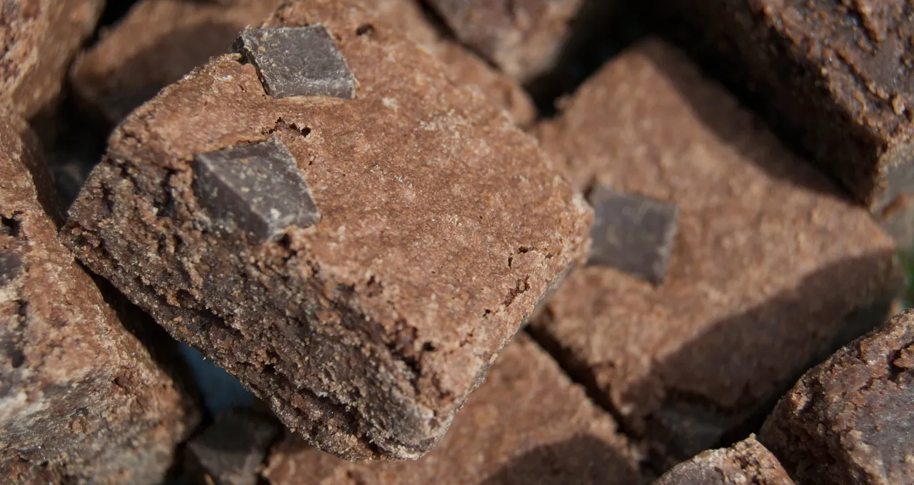 Close-up of square chocolate brownies with a crackly top and chocolate chunks