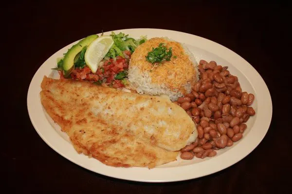 Plate of rice, stewed beans, and fried fish, with salad and avocado