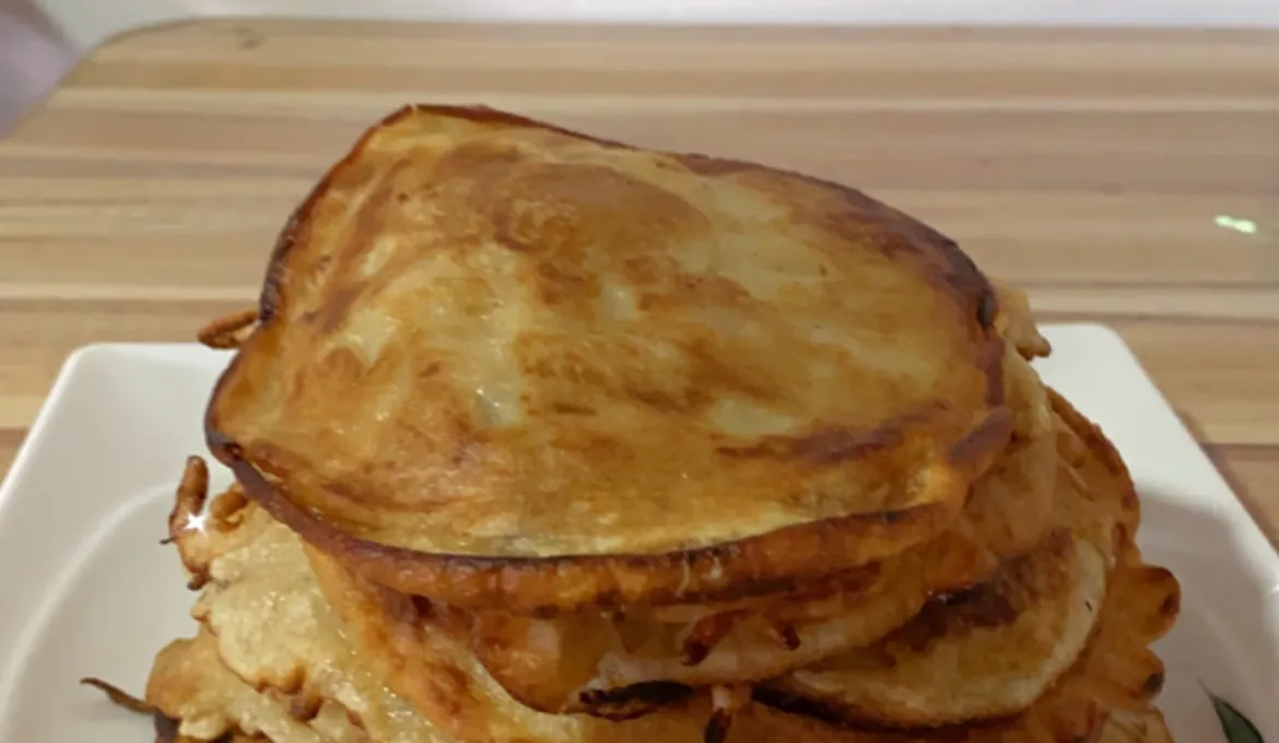 Tall stack of golden-brown pancakes on a white square plate on a wooden table