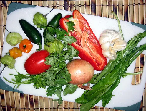 Ajíes dulces, jalapeños, bell pepper, onion, garlic, tomato, cilantro, and recao on a white board